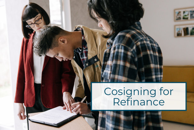 three people stand over a desk while a young man in the middle signs paperwork